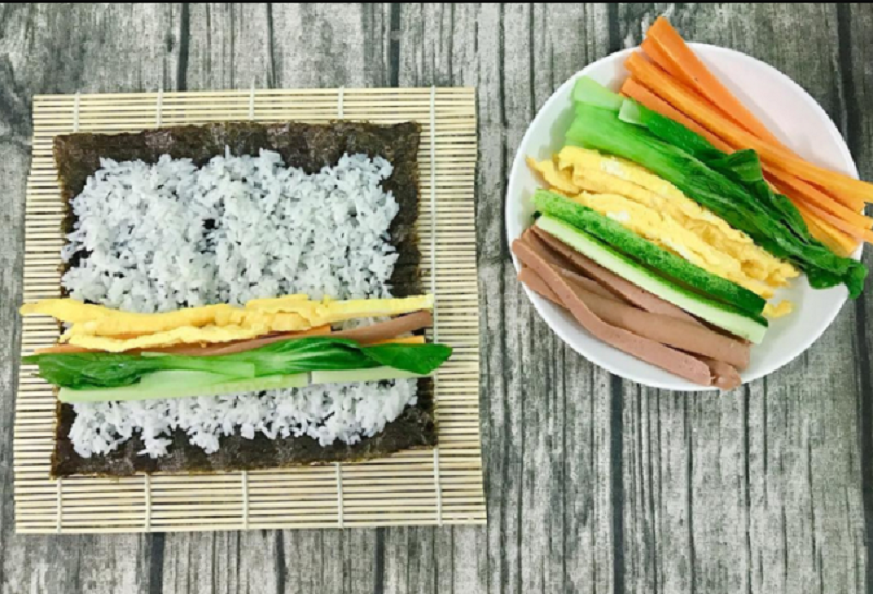 Cách cuộn cơm kimbap nhân trứng rán bằng rong biển và mành tre. 