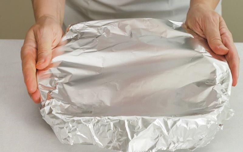 Lót giấy bạc lên khay nướng để chống dính và ủ hơi hấp cá chín đều hơn